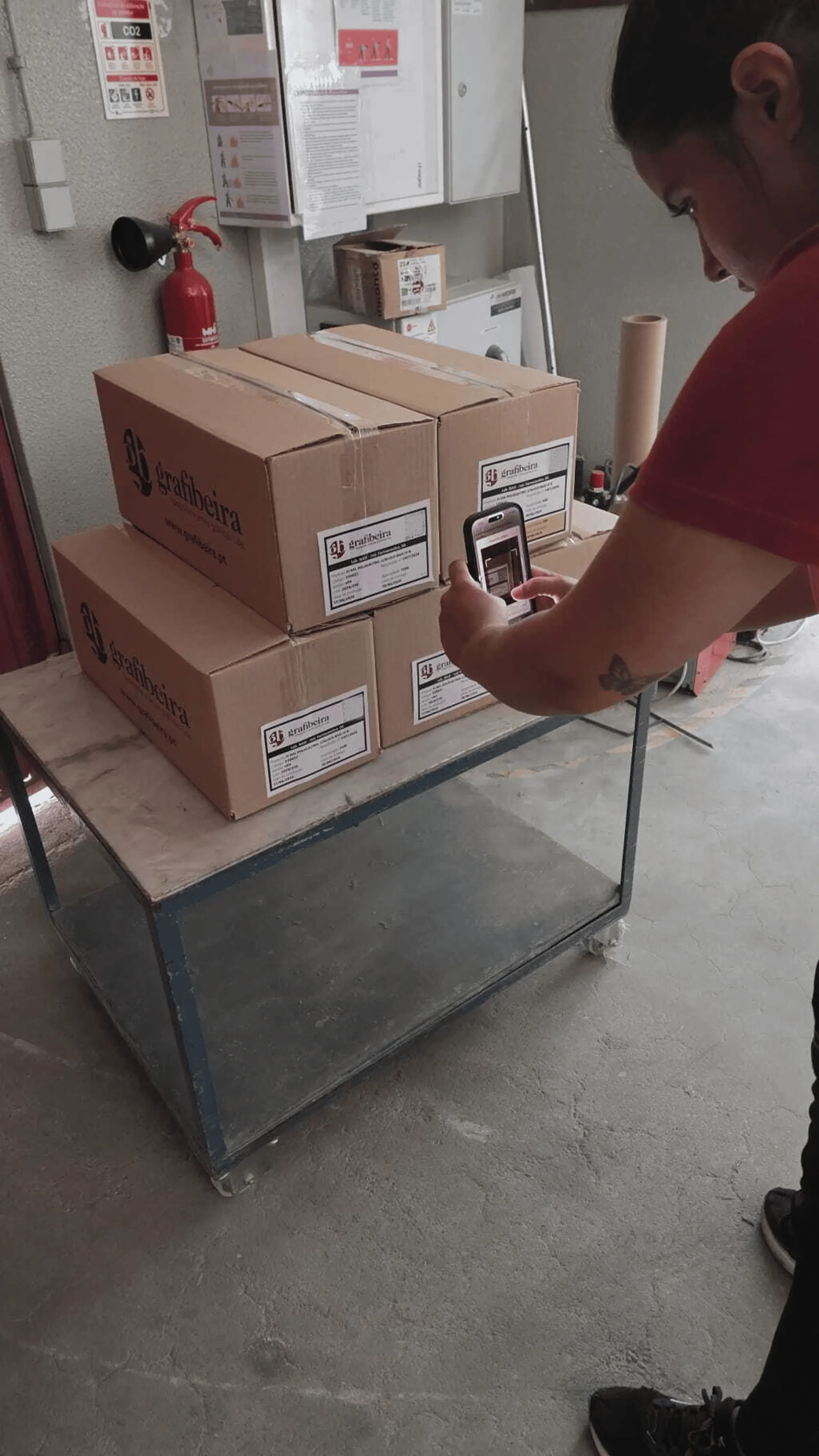 A Grafibeira worker scanning a QR code on a cardboard box on a cart
