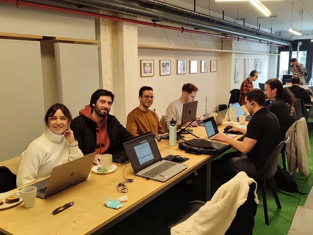 Concealed team members working together on computers in a shared space.