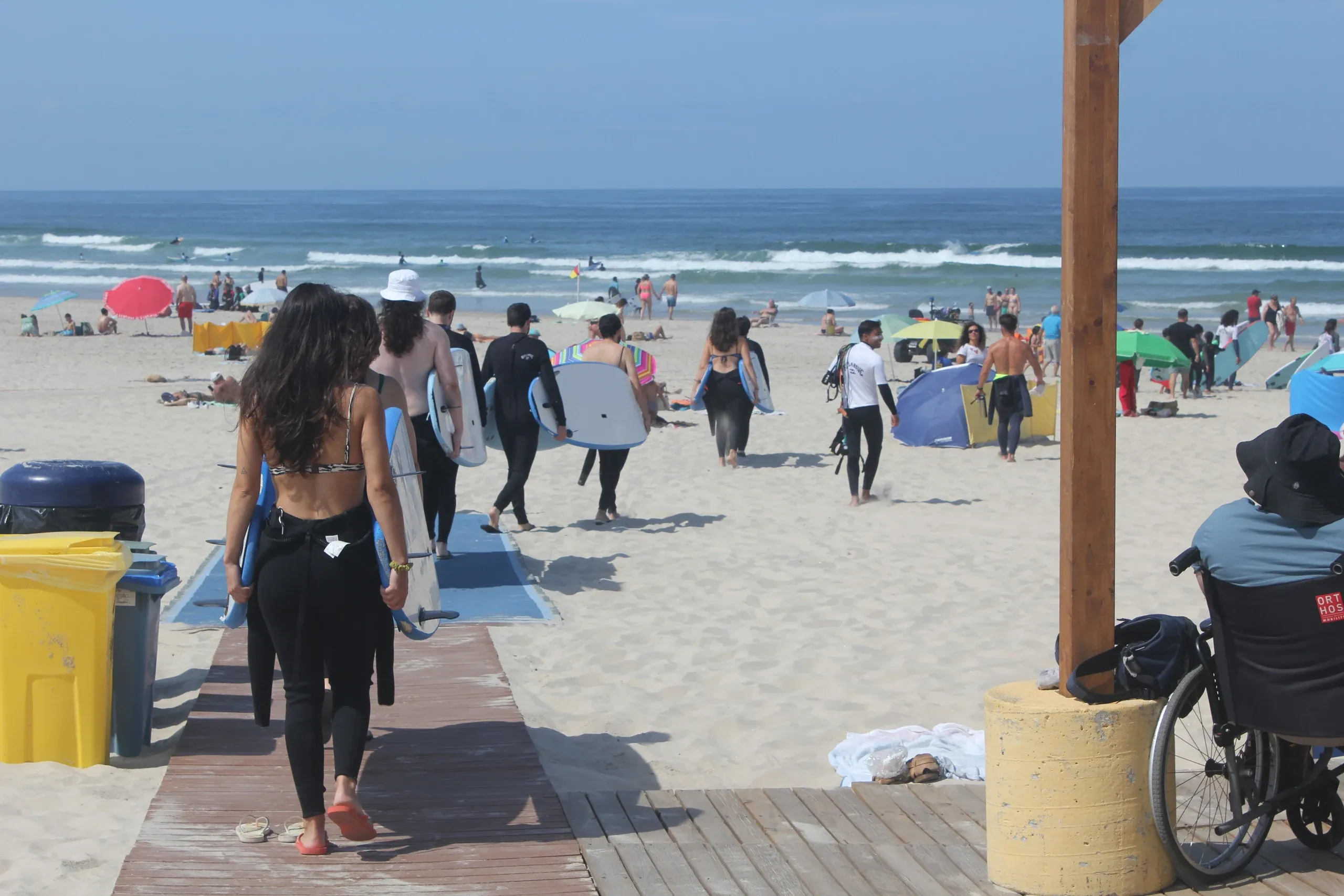 Concealed team walking to a beach holding surf boards in preparation for a surf class. They have their backs towards the camera.
