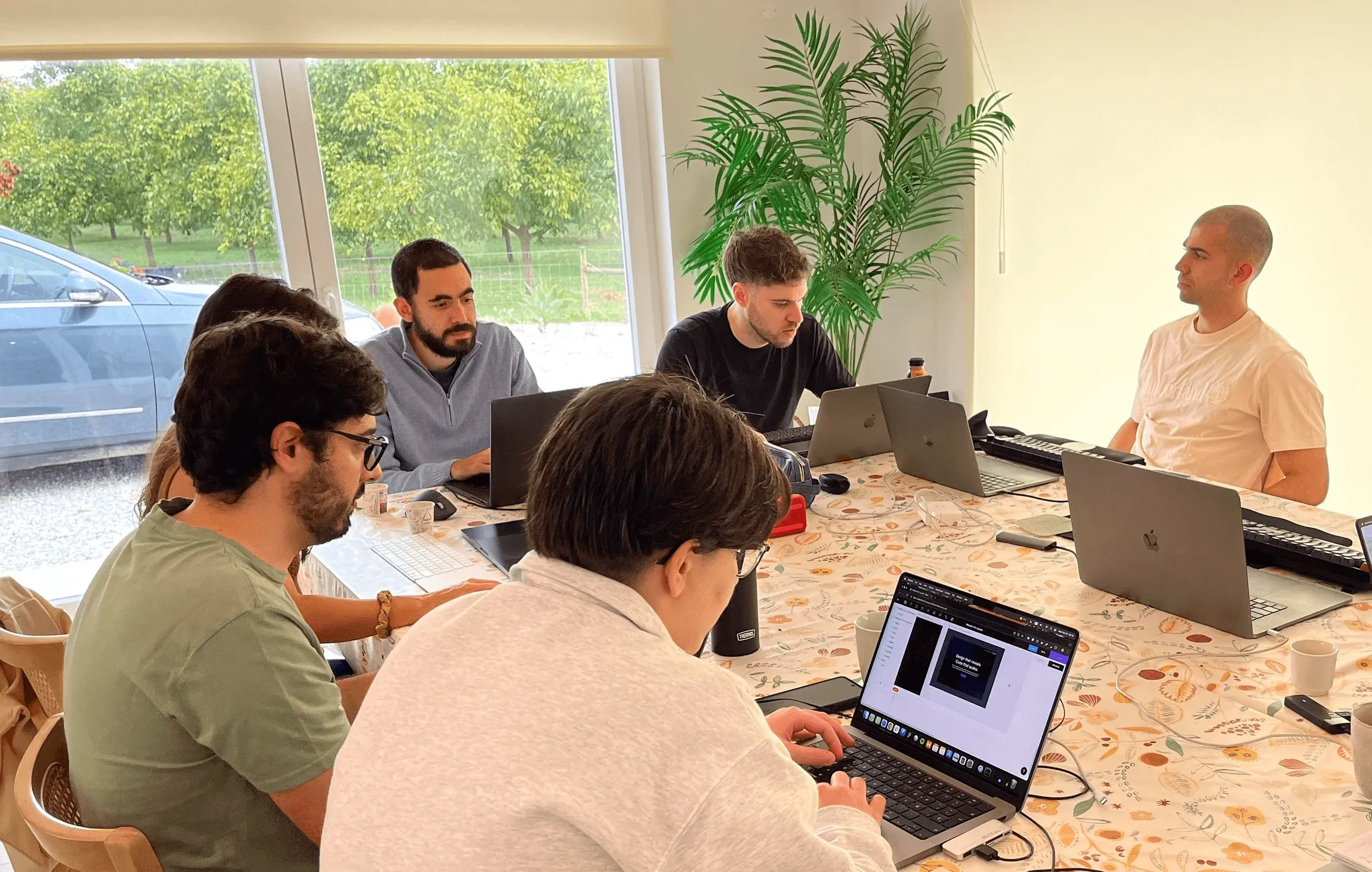 Three Concealed team members discussing a topic, where two are sitting and one, in the middle, is standing.